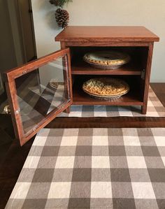 an open cabinet with two pies in it on a checkered tablecloth area