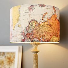 a lamp with a map on it sitting next to two framed pictures and a painting