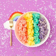 a rainbow macaroni and cheese in a bowl with a fork next to it