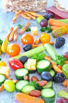 various fruits and vegetables are arranged on a table with some bread in the back ground