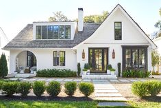 a white house with lots of windows and plants in front of the entrance to it