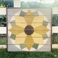 a wooden sign with a flower painted on it's side in front of a fence