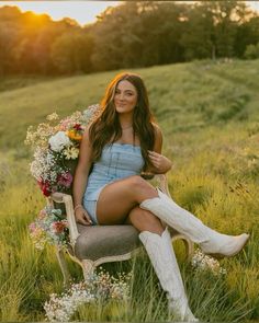 a beautiful woman sitting on top of a chair in a field