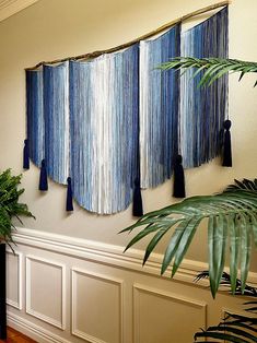 three blue tassels hanging on the wall next to a potted plant