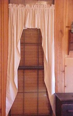 an open window in a wood paneled room with white drapes on the windowsill