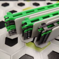 four green and white plastic pieces on top of each other with hexagonal tiles in the background