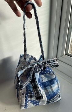 a hand holding a small blue and white bag