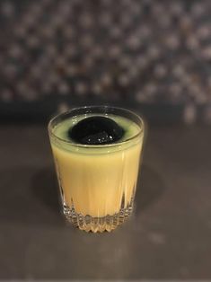 a small glass filled with liquid sitting on top of a table next to a wall