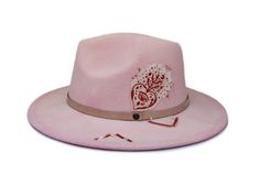 "The Santa Rita hat part of the Tucson Collection Type: Center Dent Wide Brim Fedora Adjustable Size: With a tie of a knot, adjust the fit of your hat to the ideal size from 21 ¼ to 23 ¼ inches. Dimensions: Wired Brim: 2 7/8\", Crown: 4\" Color: Pink- Sun bleached for 32 hrs. Materials: 65% Cotton, 35% Polyester Genuine Leather Hat Band Custom Juju & Moxie \"Lunar & Heart\" Illustration Patch Origin: All of our hats begin in Ecuador as the body is molded, then completed at our studio in Pink Fedora Hat, Pink Fedora, Mexican Folklore, Womens Fedora, Wool Fedora Hat, Felt Cowboy Hats, Heart Illustration, Santa Rita, Wide Brim Fedora