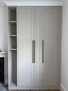 an empty room with white cupboards and wood flooring on the wooden floor next to a fireplace