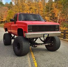 a red pick up truck with big tires on the road