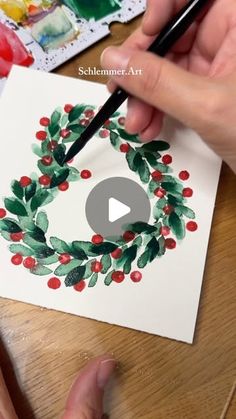 someone is painting a christmas wreath with watercolors