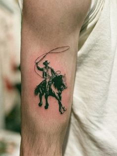 a man with a tattoo on his arm is holding a lasso while riding a horse