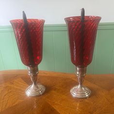 two red glass vases sitting on top of a wooden table