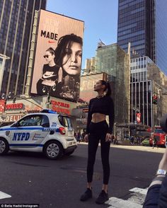 a woman standing in the middle of a busy city street with billboards behind her