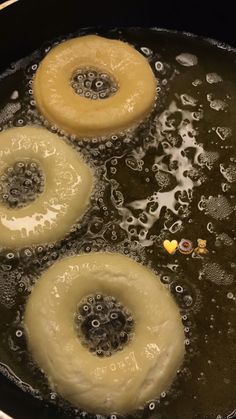 three donuts frying in oil in a pan on the stove top with water