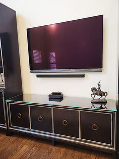 a flat screen tv mounted to the side of a wall next to a black dresser