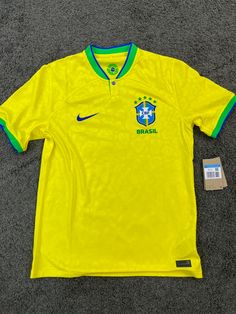 a yellow soccer jersey with the brazil national team on it and a tag in front of it