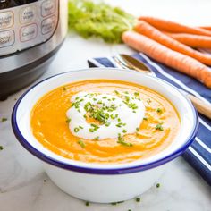 a bowl of carrot soup next to an instant pressure cooker with fresh cream on top