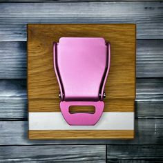 a pink chair is mounted to a wooden wall