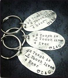 three metal key chains with words on them sitting on top of a black tablecloth