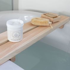 a bath tub with a wooden shelf holding a jar of soap and a brush