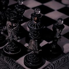 black and white photograph of chess pieces on a checkered board with an ornate design