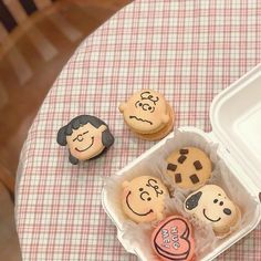 some cupcakes with faces are sitting in a box on a checkered table cloth