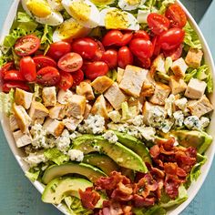 a salad with chicken, tomatoes, avocado and bacon on it in a white bowl