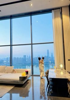 a woman standing in front of a large window looking out at the cityscape