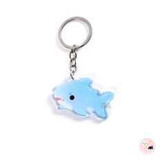 a plastic keychain with a blue shark on it's side and a white background