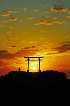 the sun is setting over an island with a person standing in front of it,