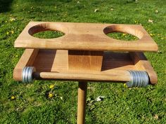 a wooden stand with two metal rings on it's sides in the middle of some grass