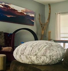 a large round pillow sitting on top of a chair in a living room next to a window