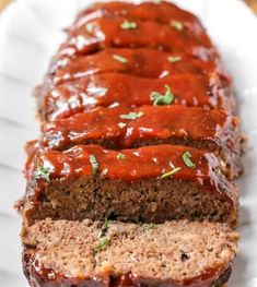 sliced meatloaf on a white plate with ketchup and green garnish