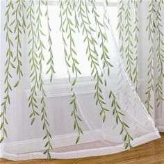 the curtains are hanging in front of the window with green leaves on them and white drapes