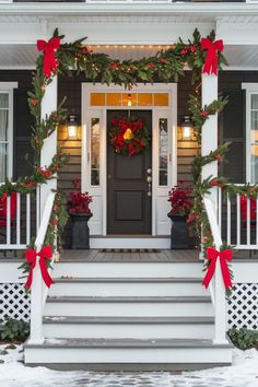 the front porch is decorated for christmas with wreaths and red bows on the steps