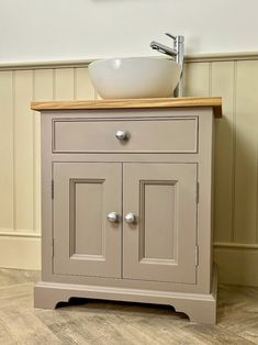 a bathroom sink sitting on top of a wooden counter next to a white bowl mounted above it