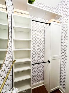 an empty closet with white shelves and open doors in front of a mirror on the wall