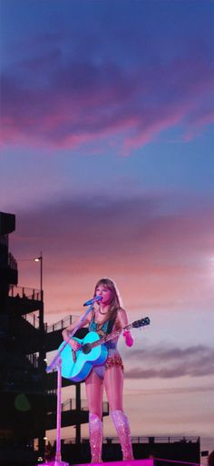 the woman is singing on stage with her guitar in front of purple and blue sky