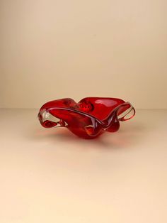 a red glass bowl sitting on top of a table