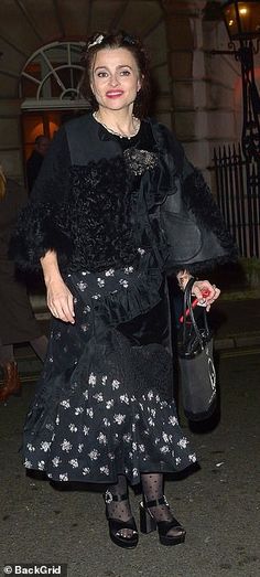 a woman in a black dress is walking down the street