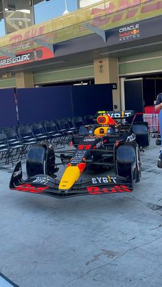 the red bull racing car is parked in front of an empty building with chairs around it