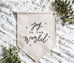 a tea towel with the words joy to the world printed on it next to some plants