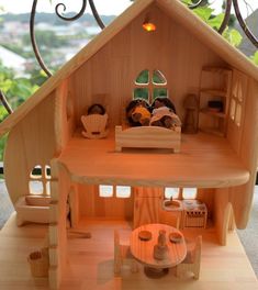 a wooden doll house with furniture and accessories on the floor in front of a window