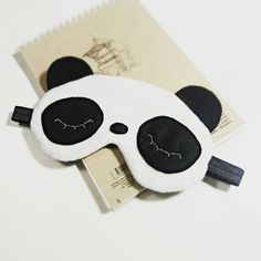 a black and white panda bear sleeping mask on top of a piece of paper with eyes closed