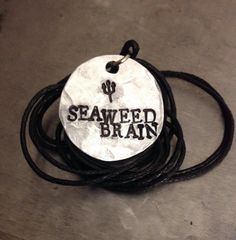 a black and white necklace with the word seaweed blair on it sitting on top of a table