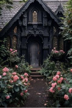 an old gothic - style house is surrounded by lush greenery and pink flowers in front of the door