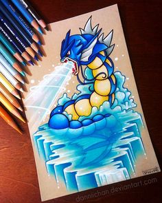 a drawing of a blue and yellow pokemon sitting on top of a table next to colored pencils