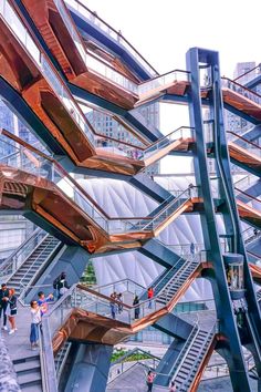 several people are walking up and down the escalators in a building with many stairs